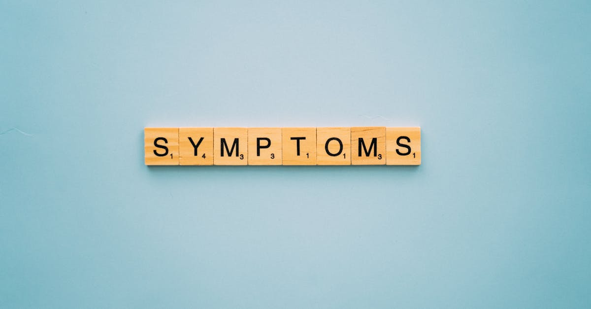 Scrabble tiles spelling 'SYMPTOMS' on a blue background, symbolizing health concepts.